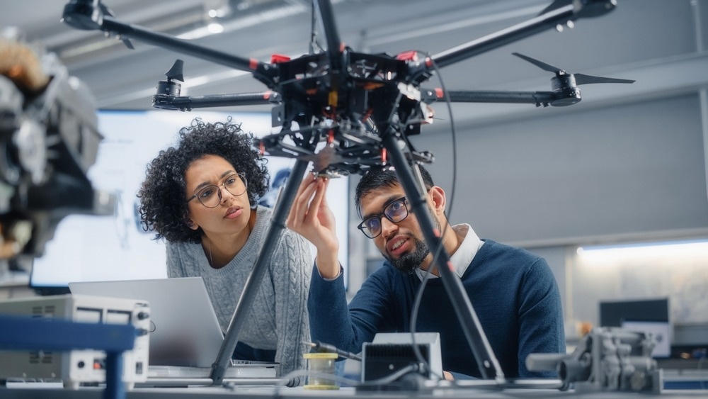 Skilful Male Engineer with Semiconductor Gives Advice to Black Female Computer Developer While She is Writing Code for Drone Control.