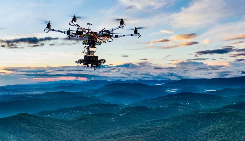 The drone with the professional cinema camera flying over the misty mountains at sunset.
